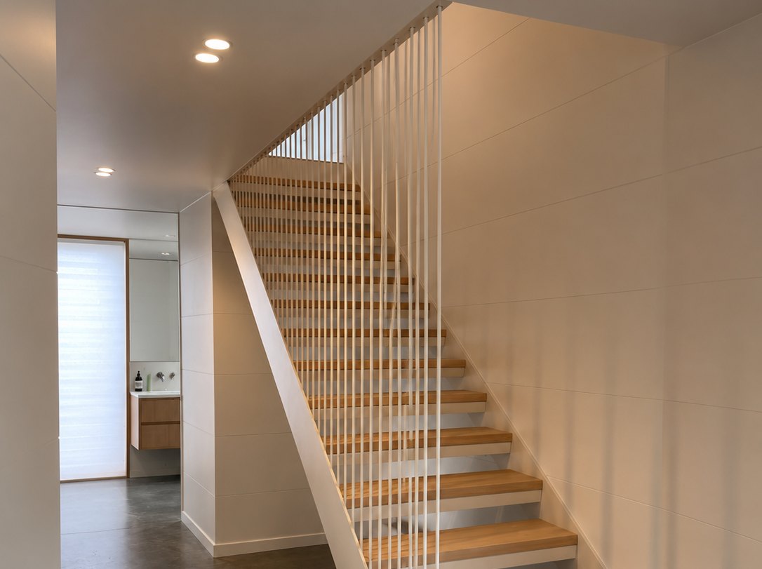 Floating oak-tread staircase with a fine white steel-rod balustrade in a home at Cass Bay, Christchurch
