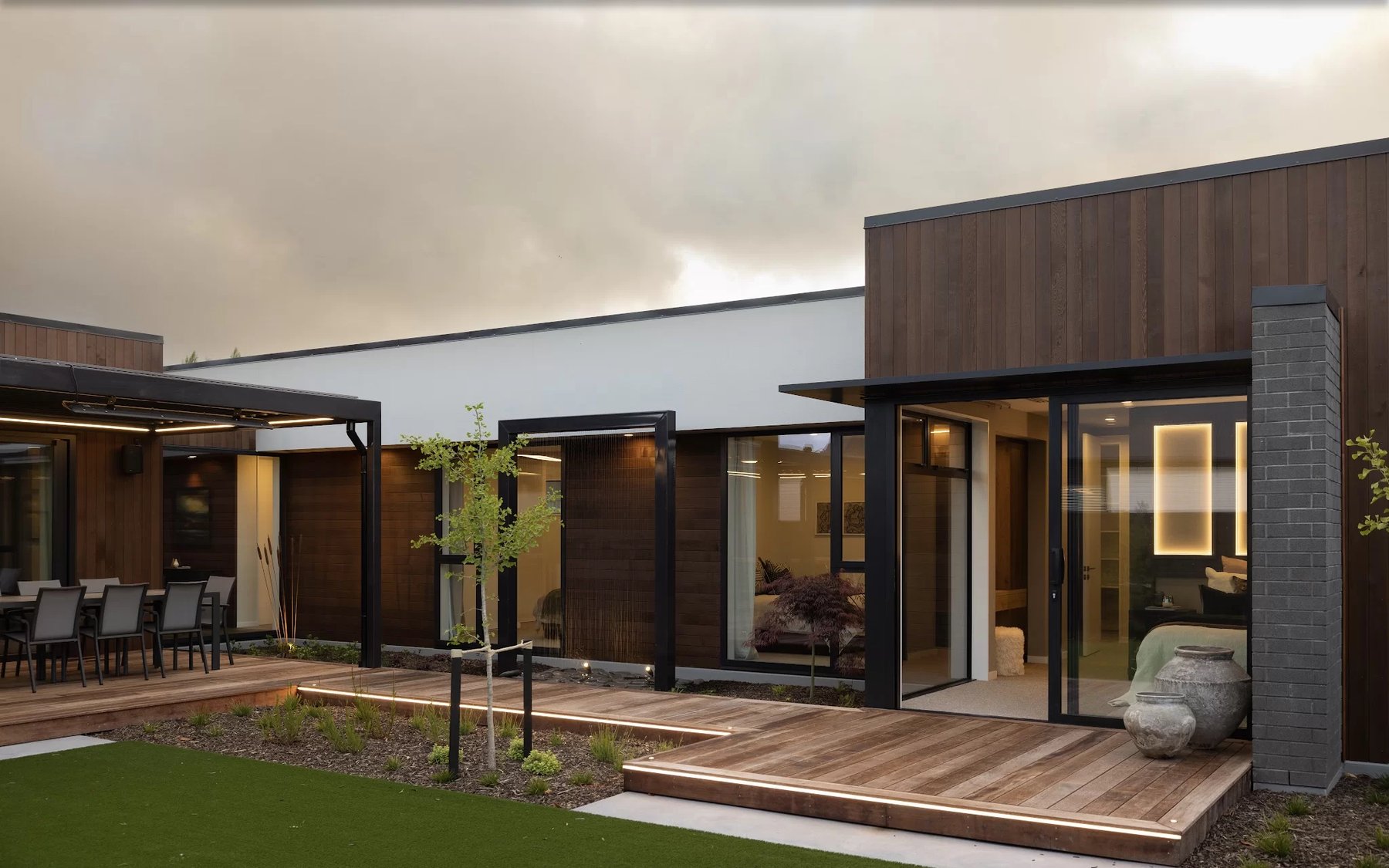 Steel pergola and outdoor rooms at a Hallmark Homes showhome at dusk