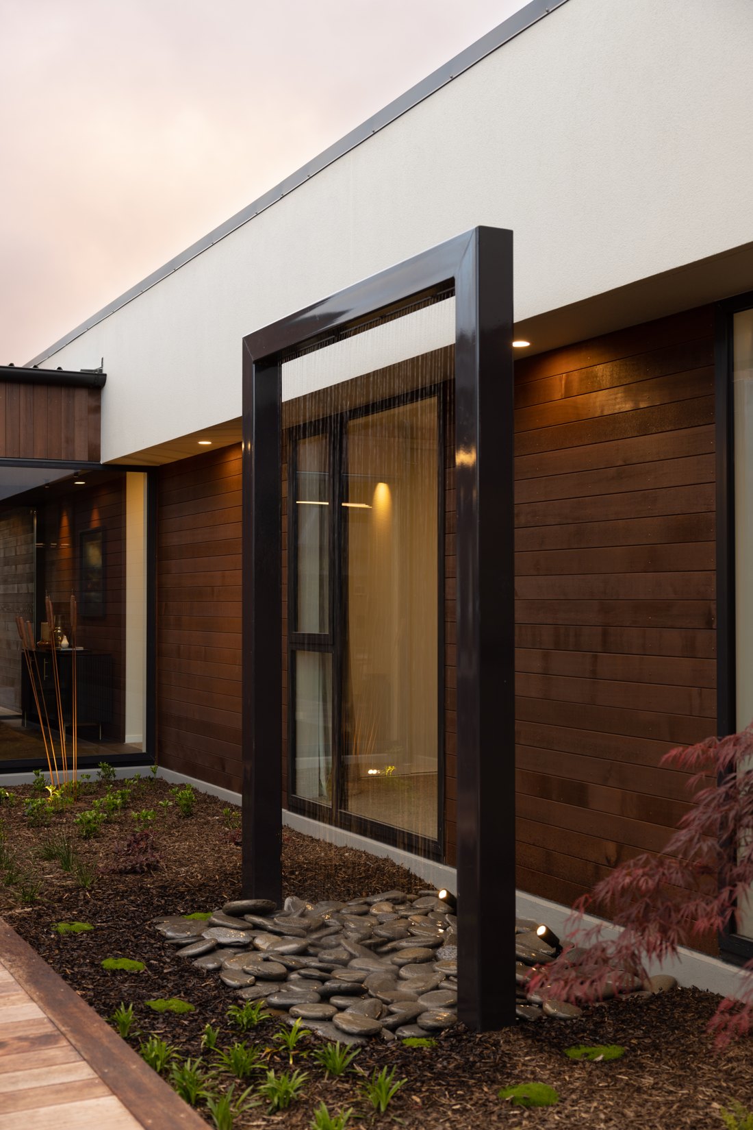 Steel water feature with a fine water curtain falling onto river stones, Hallmark Homes Oakbridge showhome