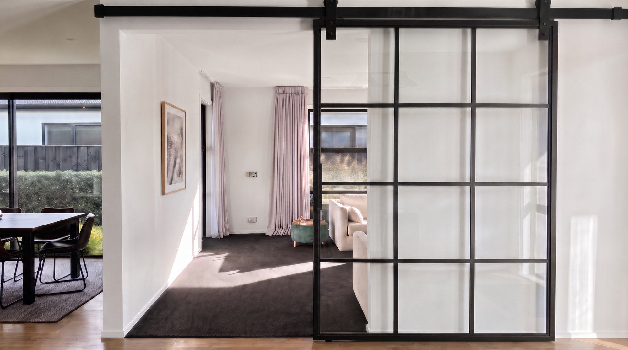 Black steel Crittall-style sliding barn door with frosted glass in a modern Christchurch home, by ARC Design Studio