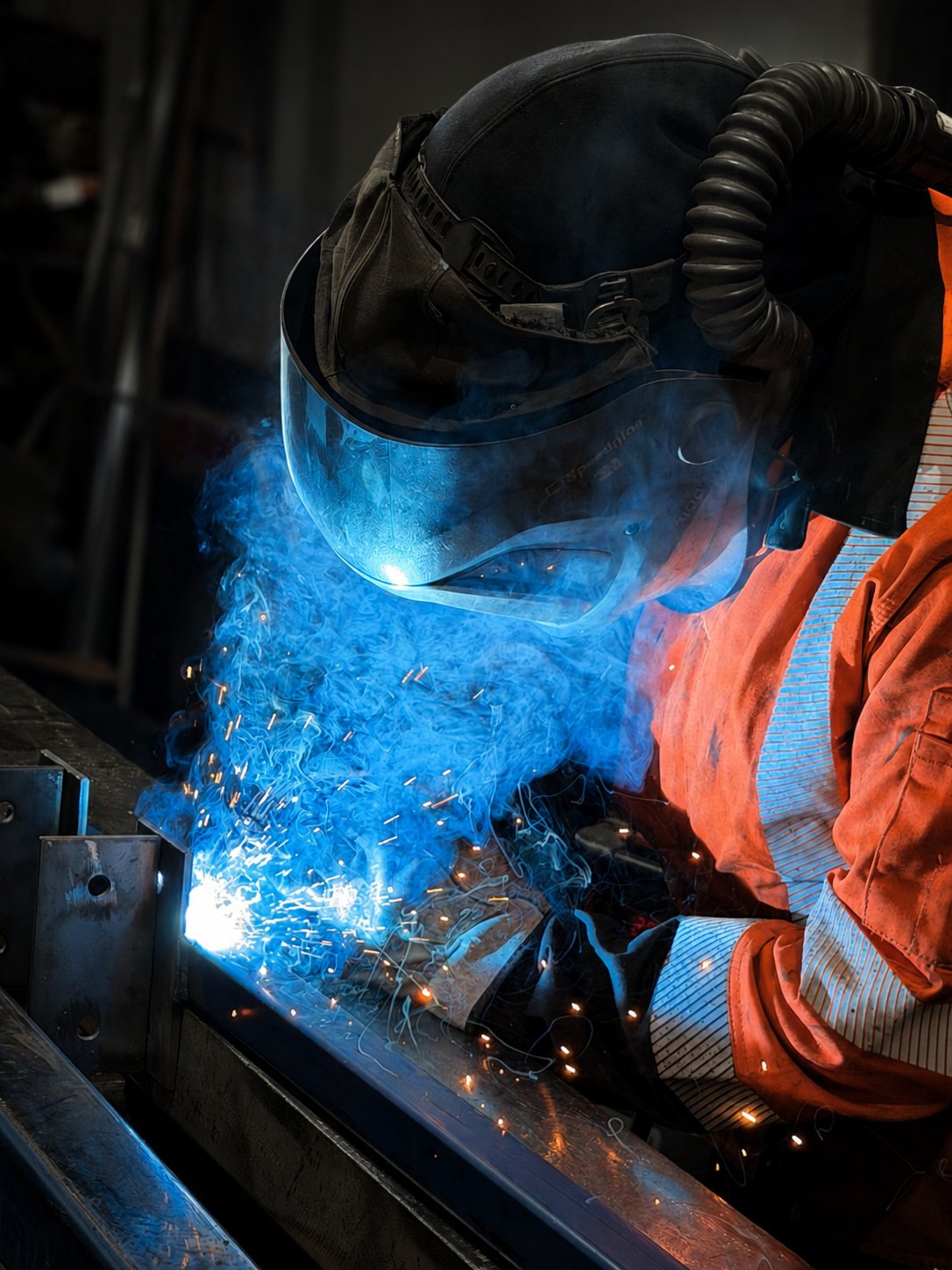 A welder fabricating architectural steel in the Bromley Steel workshop, sparks and blue arc light